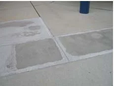 A sidewalk of concrete squares, one freshly poured and bright white